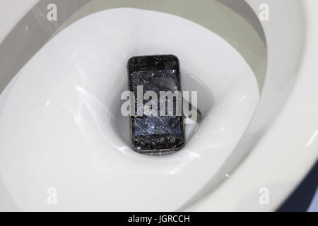 Broken mobile phone dropped into toilet bowl Stock Photo