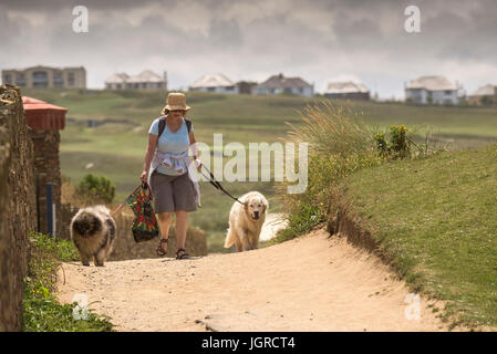 A woman walking her two dogs on footpath on The Headland in Newquay, Cornwall.