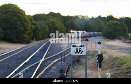 A diesel locomotive pulling coal trucks or wagons through the Southern Highlands of New South Wales in Australia in the early evening for export Stock Photo