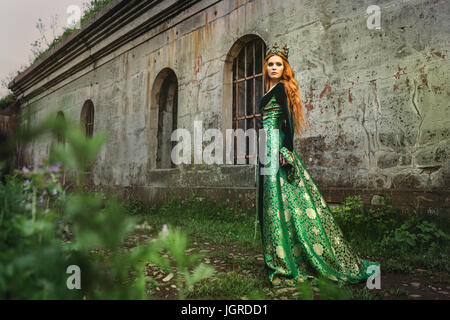 Red-haired woman in a green medieval dress near the castle Stock Photo