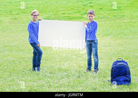 Children with blank white placard board outdoors Stock Photo