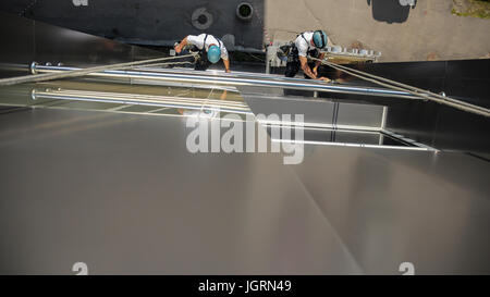 A team of window washers working on a tall office building facade. Stock Photo
