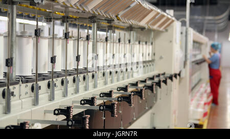 Row of automated machines for yarn manufacturing. Yarn thread running in the machine. Stock Photo