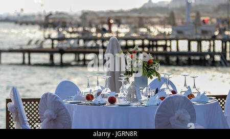 Luxury wedding reception by the sea. Wedding table with a beautiful sea view.  Wedding reception place ready for guests. Stock Photo