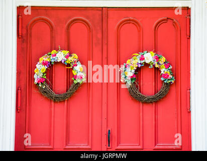 Aged red church doors with flowering wreaths Stock Photo