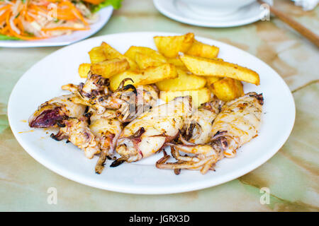 Grilled squid with french fries on a plate. Seafood meal Stock Photo