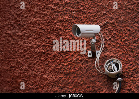 CCTV security camera and dark red wall with white wires. Security camera Stock Photo