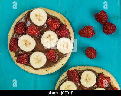 Pancakes with Chocolate Spread With Banana and Raspberries Against a Blue Background Stock Photo