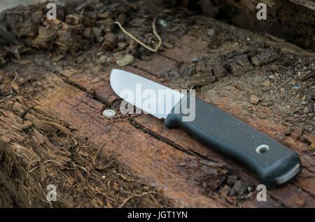 Outdoor knife on wood log. Brown wood. Sweden knife. Stock Photo