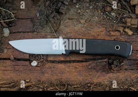 Outdoor knife on wood log. Brown wood. Front view. Sweden knife. Stock Photo