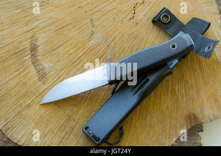 Fix knife with plastic case on wood stump. Oak wood. Stock Photo