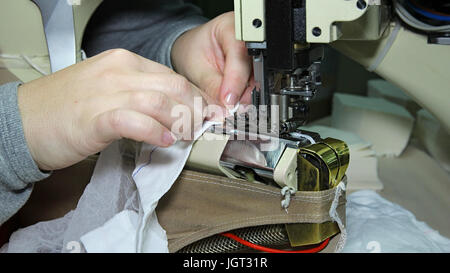 Close up portrait of hands of seamstress sewing using industrial sewing machine. Stocking manufacturing in a factory. Stock Photo