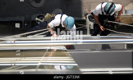 Workers hanging on climbing ropes and working together.