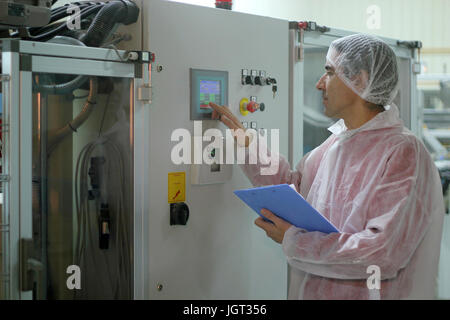 Worker using control panel of the industrial machine. Stock Photo