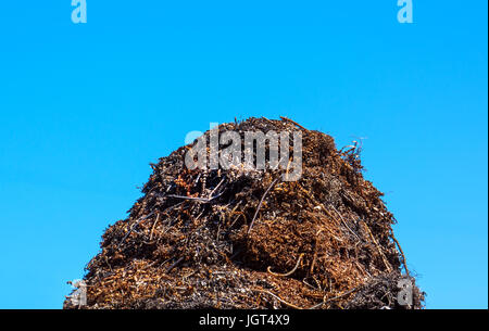 A pile of garbage on blue sky background. Metal debris on a solid blue background. Stock Photo