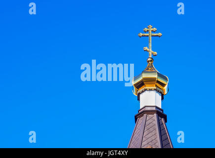 The Golden dome of an Orthodox temple on background of blue sky and clouds. Golden cross on the dome of the temple. Stock Photo