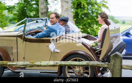 Bride and Groom travelling in an old car on their wedding day. Happy couple. Getting married in the UK. Newly weds. Just married. Stock Photo
