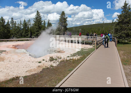 People are walking on the boardwalk of Fountain Paintpot Trail next to the Red Spouter Geyser in the Lower Geyser Basin in Yellowstone National Park Stock Photo