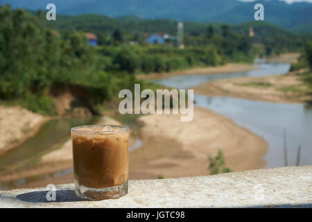 Iced coffee or caffe latte in front of a nice blurred landscape in Vietnam, Phong NhaKe Bang Nationalpark. Stock Photo