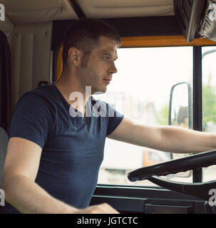 Male trucker in cabin of his yellow truck. Stock Photo
