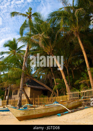 filipino boat on the beach under the palmtrees near the traditional  hut Stock Photo