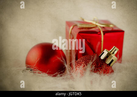 Selection of red and gold Christmas ornaments on white fake fur with yellowed and weathered vintage parchment effect. Stock Photo