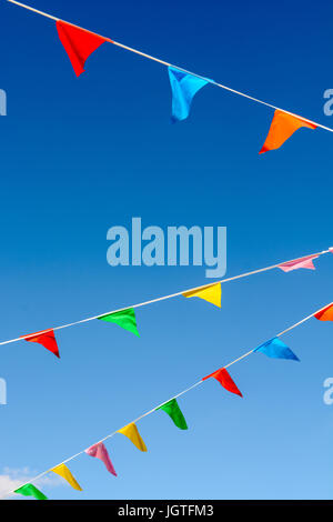 Pink and blue flags blowing in the wind against a blue cloudy sky ...