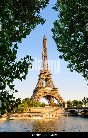 The Eiffel tower in Paris, France, seen from the Debilly pier at sunset with the Iena bridge, the river Seine and tourist shuttles in the foreground. Stock Photo