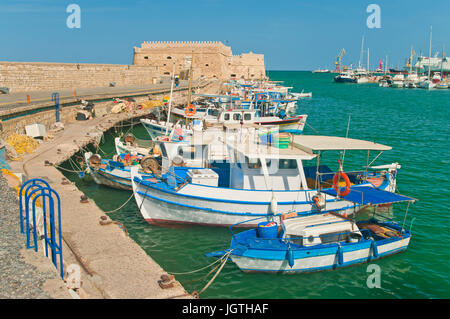 small blue and white fishing boats moored at Koules Fortress in Heraklion, Crete, Greece Stock Photo