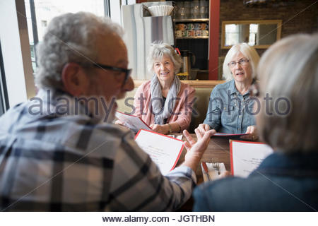 Senior friends dining, looking at menus in diner booth