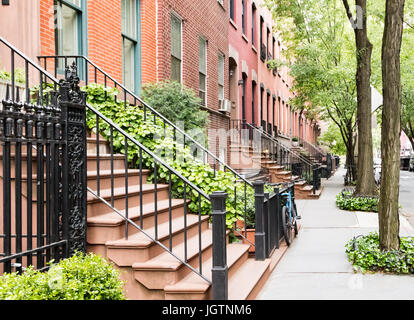 Scenic tree lined street of historic brownstone buildings in the West Village neighborhood of Manhattan in New York City, NYC USA Stock Photo