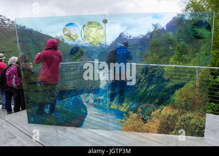 Tourists looking at view by Eagles Road viewpoint sign overlooking Geirangerfjorden. Geiranger, Sunnmøre region, Møre og Romsdal county, Norway, Stock Photo