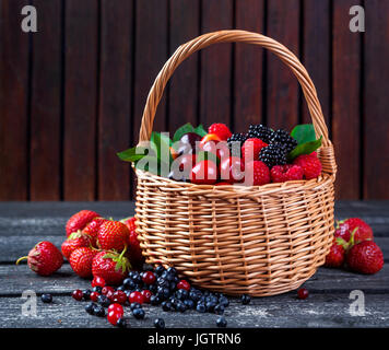 Berries mix in basket on rustic wooden background Stock Photo