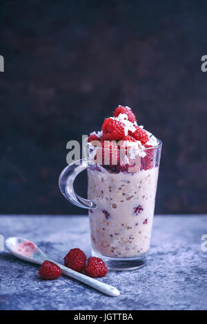Overnight oats in almond milk topped with fresh raspberries and coconut flakes Stock Photo