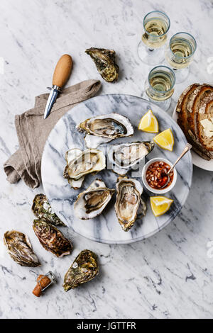 Open shucked Oysters with lemon, bread, butter and champagne on white marble background Stock Photo