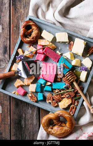Variety of colorful holland cheese traditional soft, old, pink basil, blue lavender served with pecan nuts, honey, lavender flowers, pretzels bread on Stock Photo