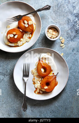 Roasted pears in caramel sauce served with yogurt and almonds Stock Photo