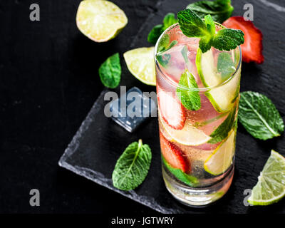 fresh lemonade with strawberry, lime and mint on dark stone background. Cold summer strawberry drink with mint and ice. Strawberry mojito in glass and Stock Photo