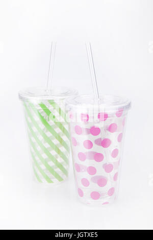 Green and pink plastic tumblers on a white surface. Tumblers isolated on white background. Stock Photo