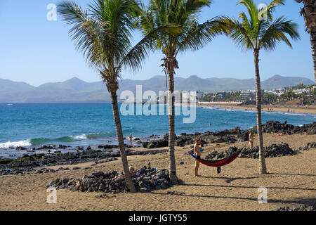 Badegaeste zwischen kleinen Schutzmauern (Windschutz) aus Lavasteinen, Playa Grande, grosser Badestrand in Puerto del Carmen, Lanzarote, Kanarische In Stock Photo