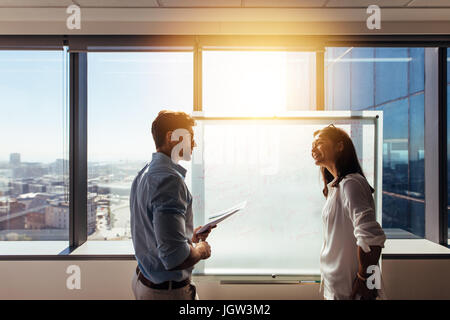 Two business colleagues working on a business plan. Business investors writing their ideas on whiteboard during discussion in boardroom. Stock Photo