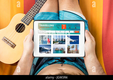 Young man with tablet device consulting a travelling website, lying on a hammock. Stock Photo