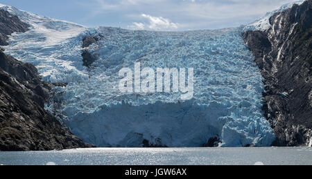 The blue mass of ice that makes up Blackstone Glacier pushes into the sea on a sunny day Stock Photo