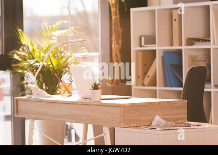 workspace with laptop computer in modern empty office with sunlight Stock Photo