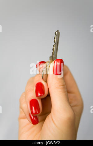 Beautiful female fingers with red nails hold the key to the apartment. Stock Photo