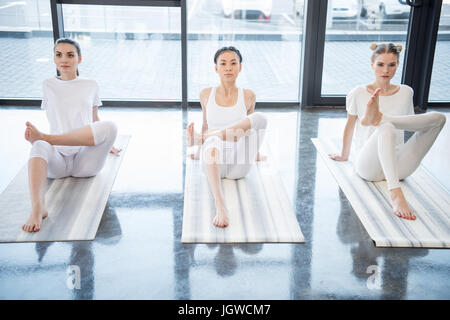 Concentrated young women performing yoga position together on yoga mats Stock Photo