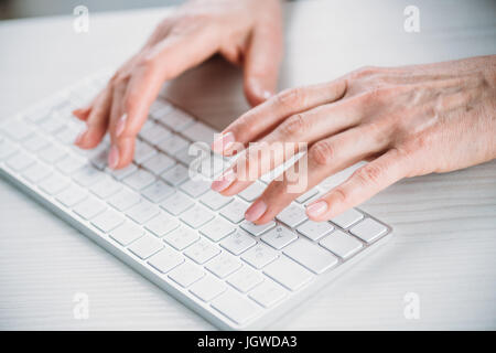 close up view of woman typing on keyboard on tabletop Stock Photo