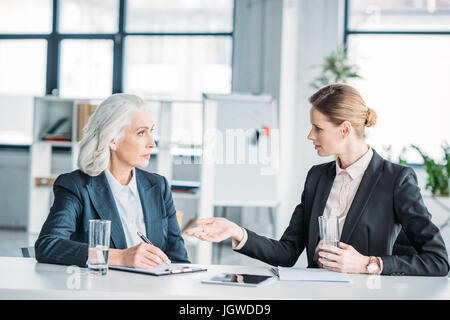 two businesswomen gesturing and discussing business project on meeting in office Stock Photo
