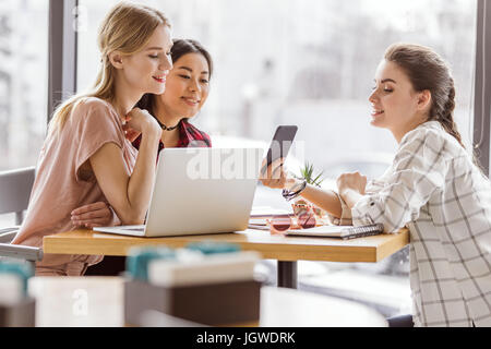 group of stylish friends spending time together in cafe Stock Photo