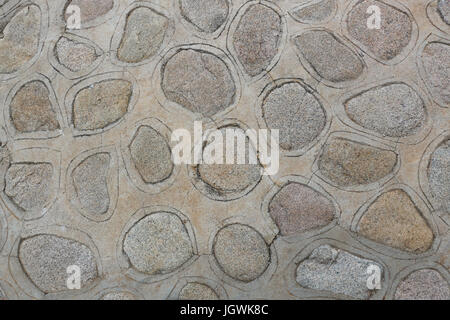 Closeup of a sidewalk or patio constructed by sinking rocks into cement, and incising a pattern around each rock; good background or wall paper. Stock Photo